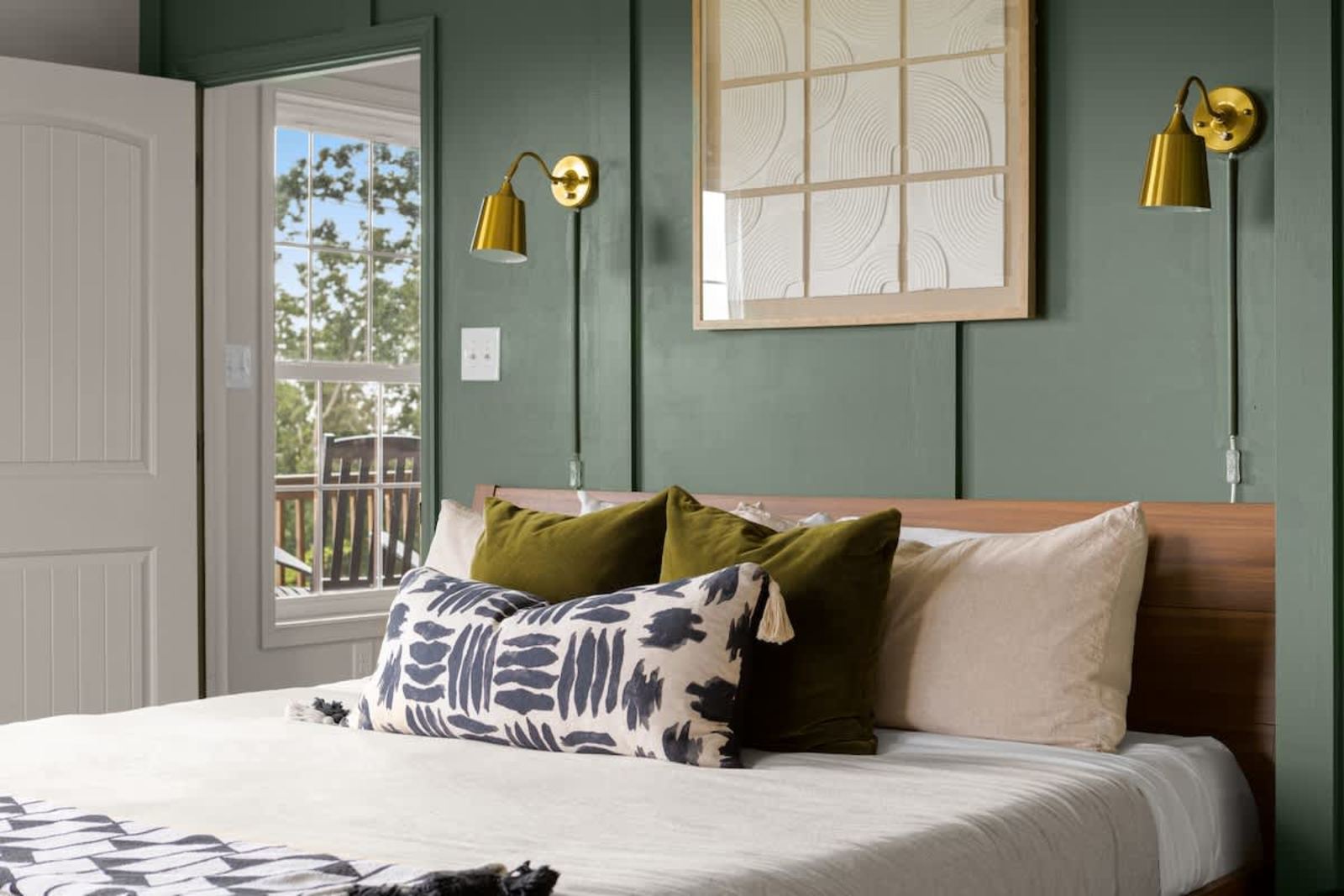 Green paneled bedroom with private deck access and a treetop view
