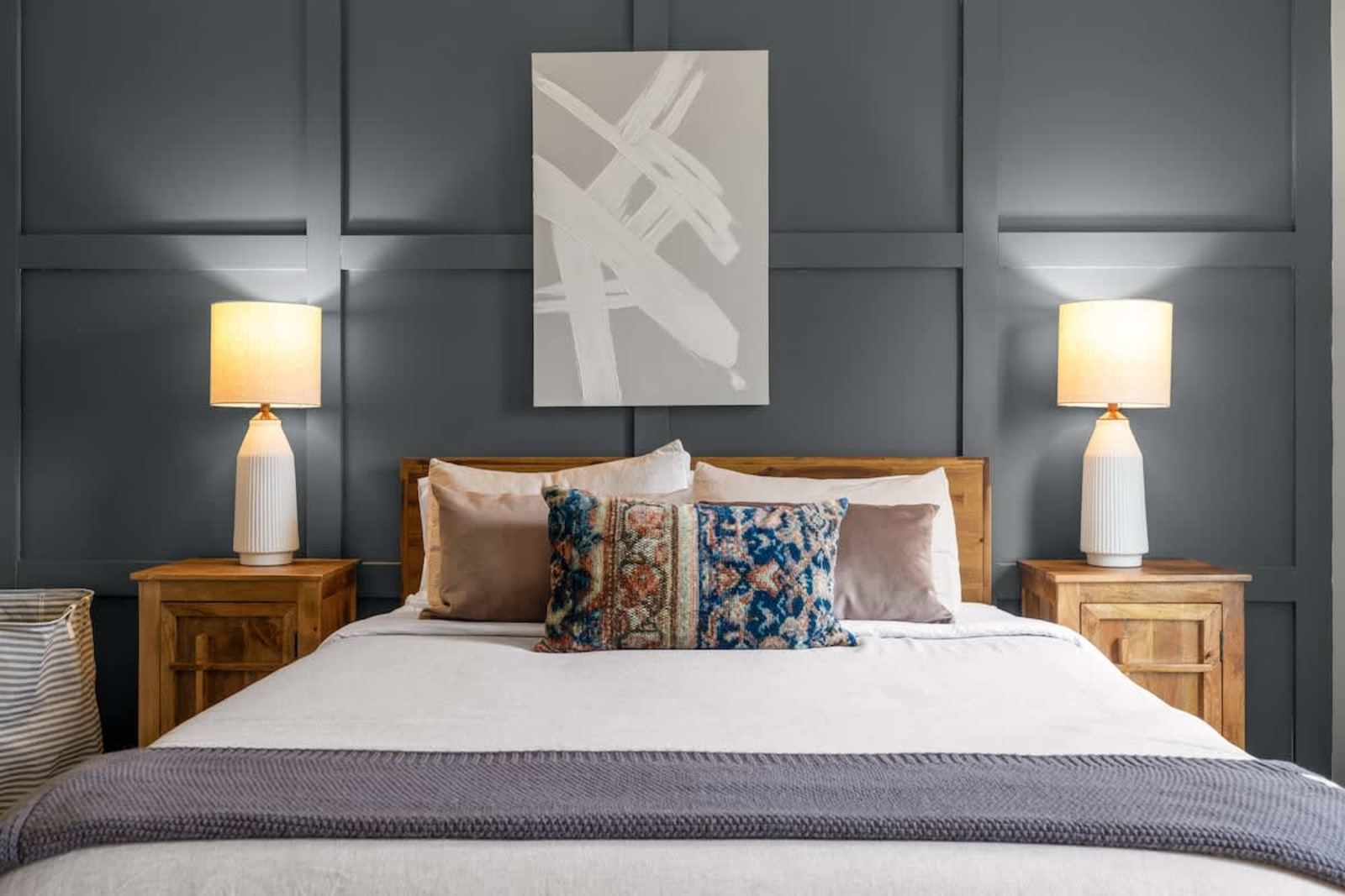 King bedroom with navy paneled walls and warm bedside lighting