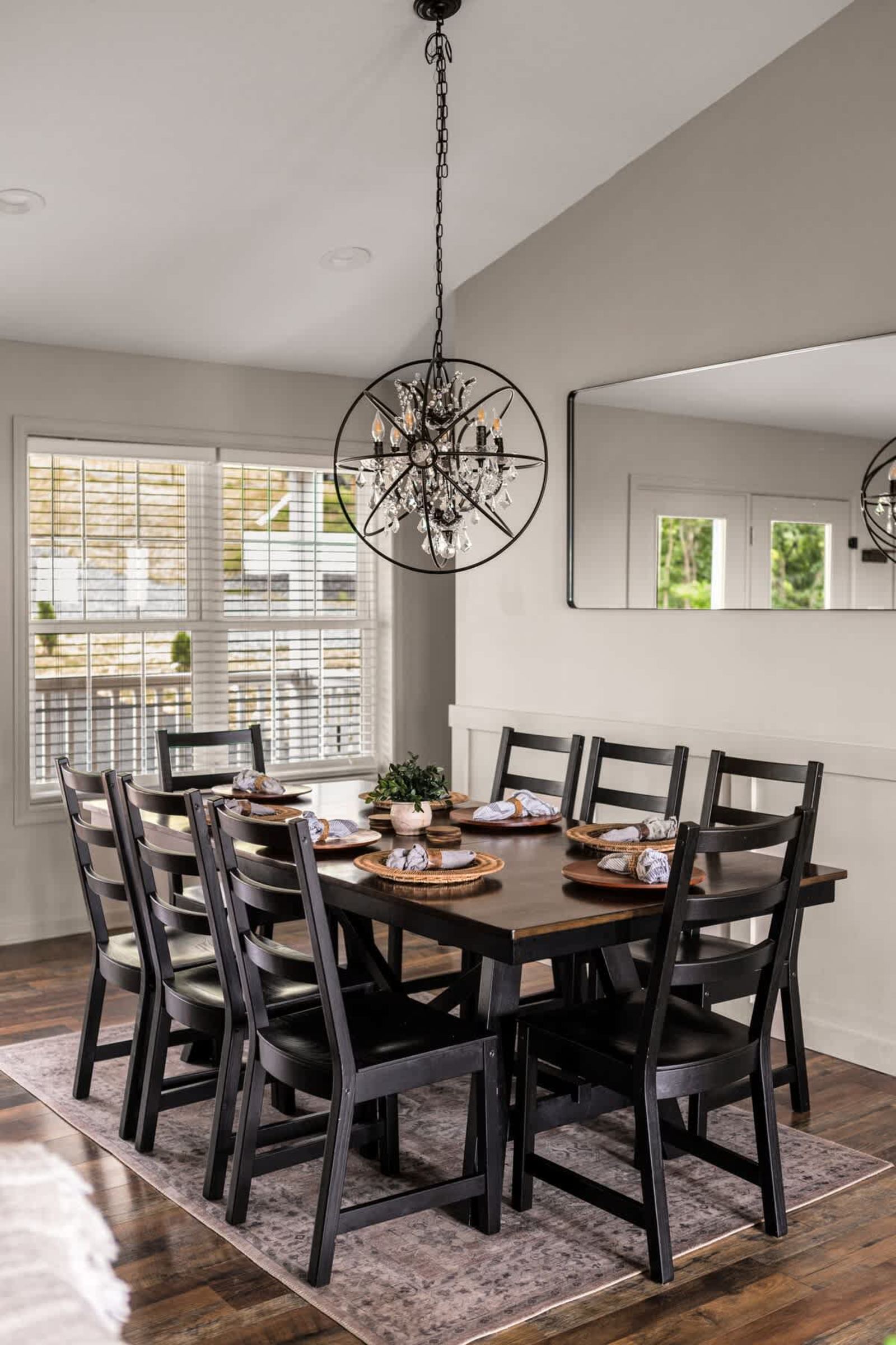 Dining table set for eight under an iron orb chandelier