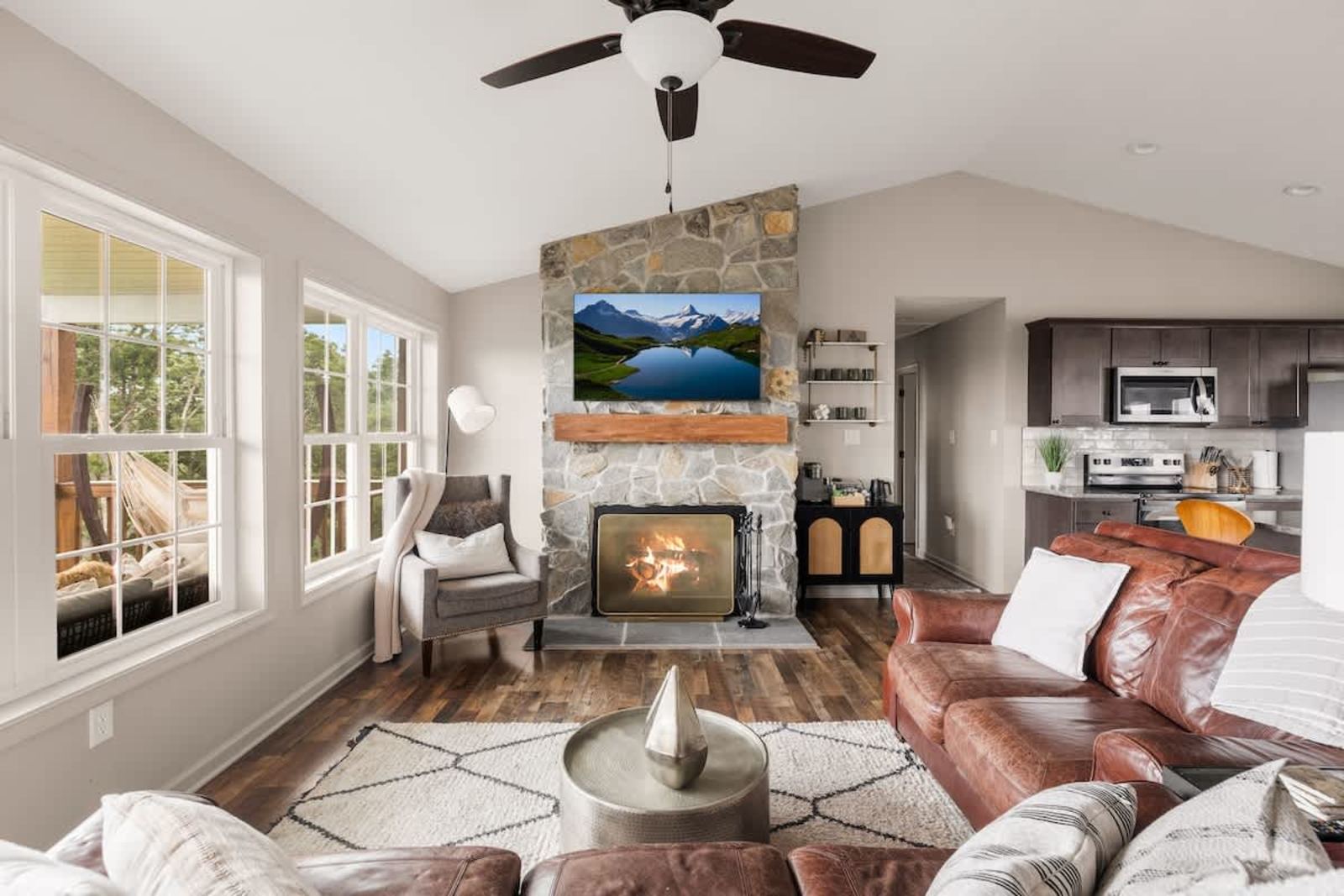 Living room with a stone wood-burning fireplace under a vaulted ceiling