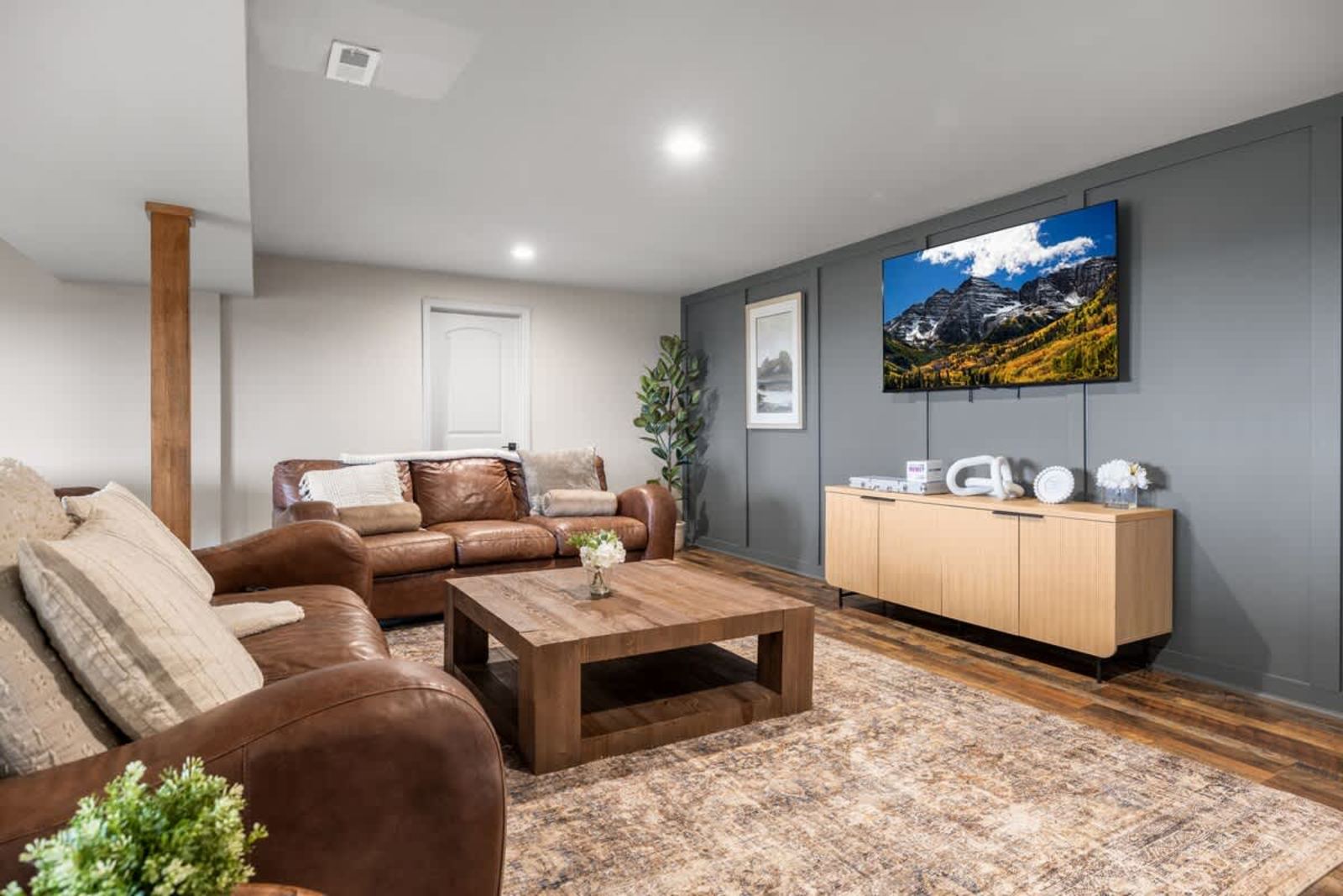 Lower-level family room with leather sofas and a large smart TV