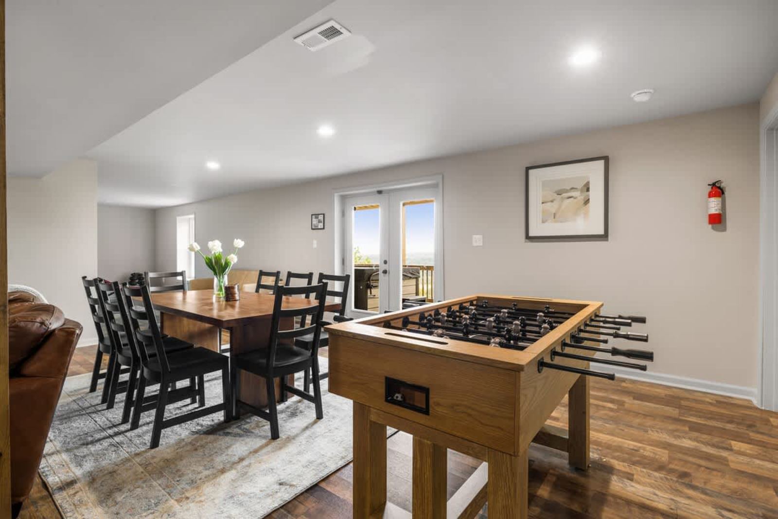 Lower-level game room with a foosball table, dining, and French doors out